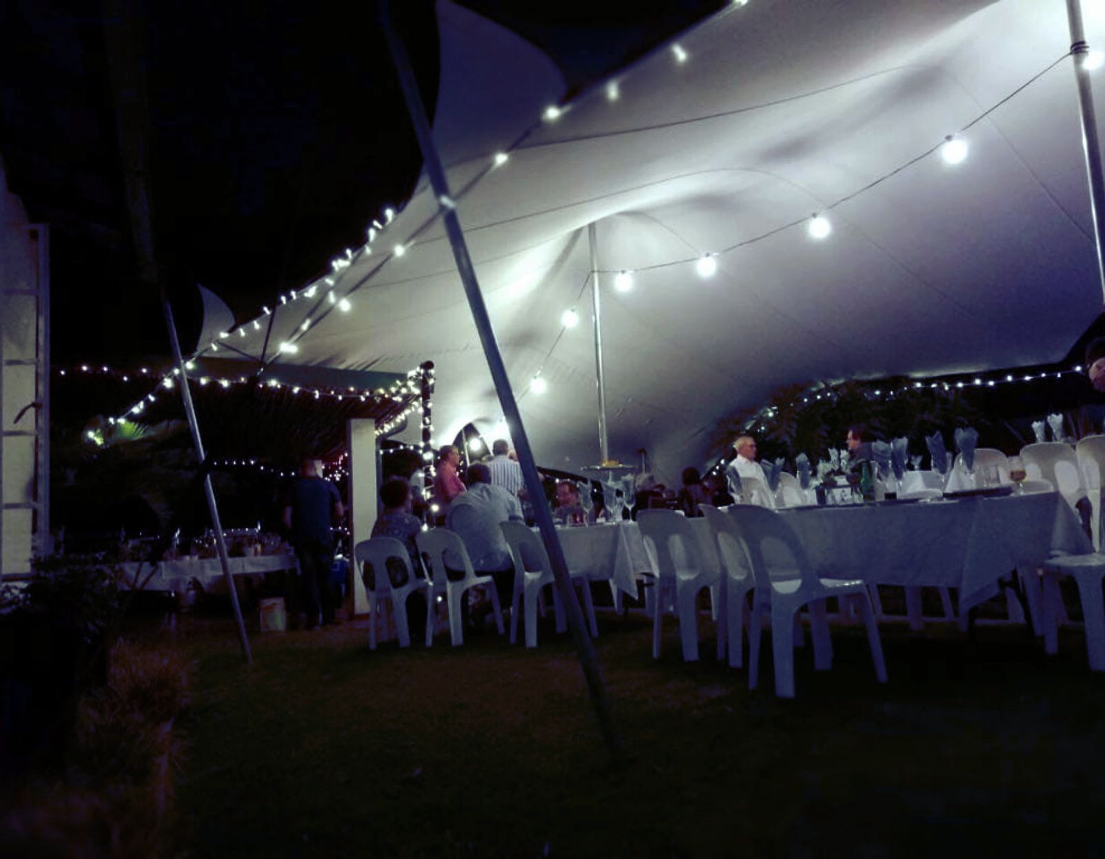Tent Set Up In A Garden With Lights And Tables And Chairs.