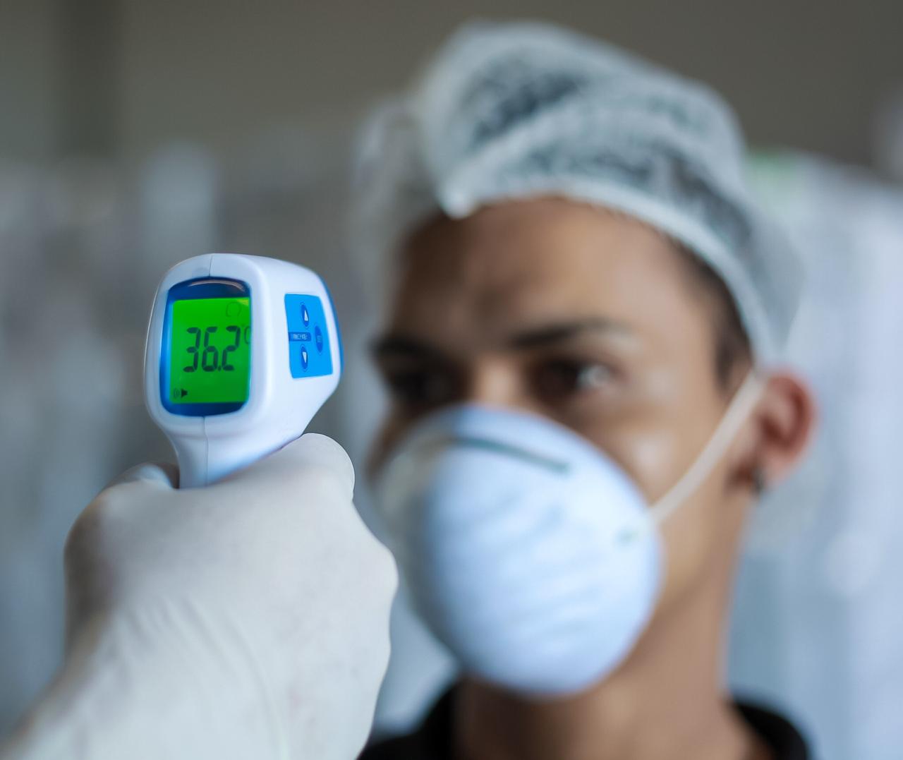 A worker being scanned with a non-contact thermometer to measure his tempreture to work in the hygiene factory