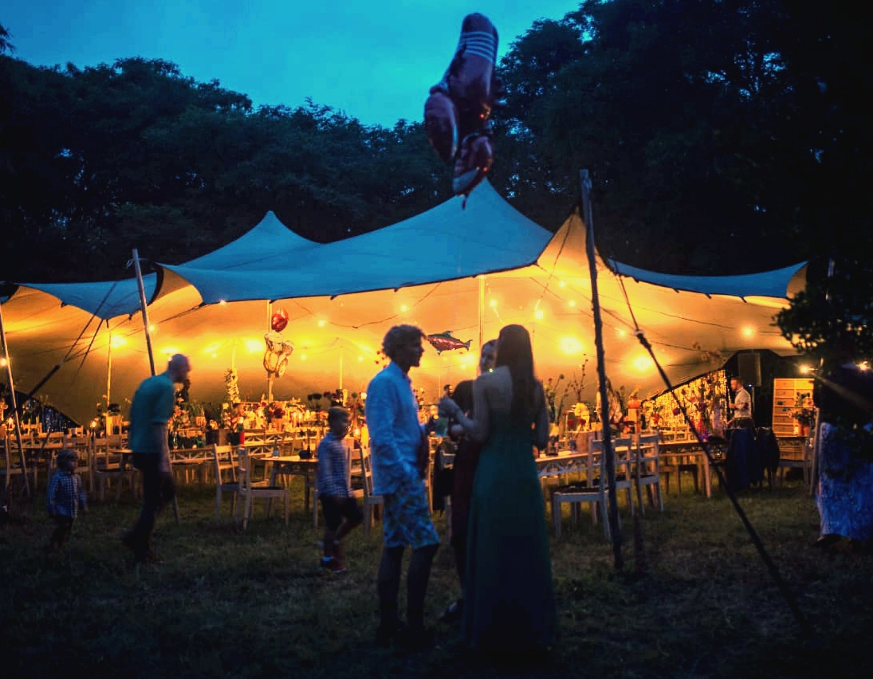 Outdoor Wedding In A Stretch Tent With Lights And Tables And Chairs.