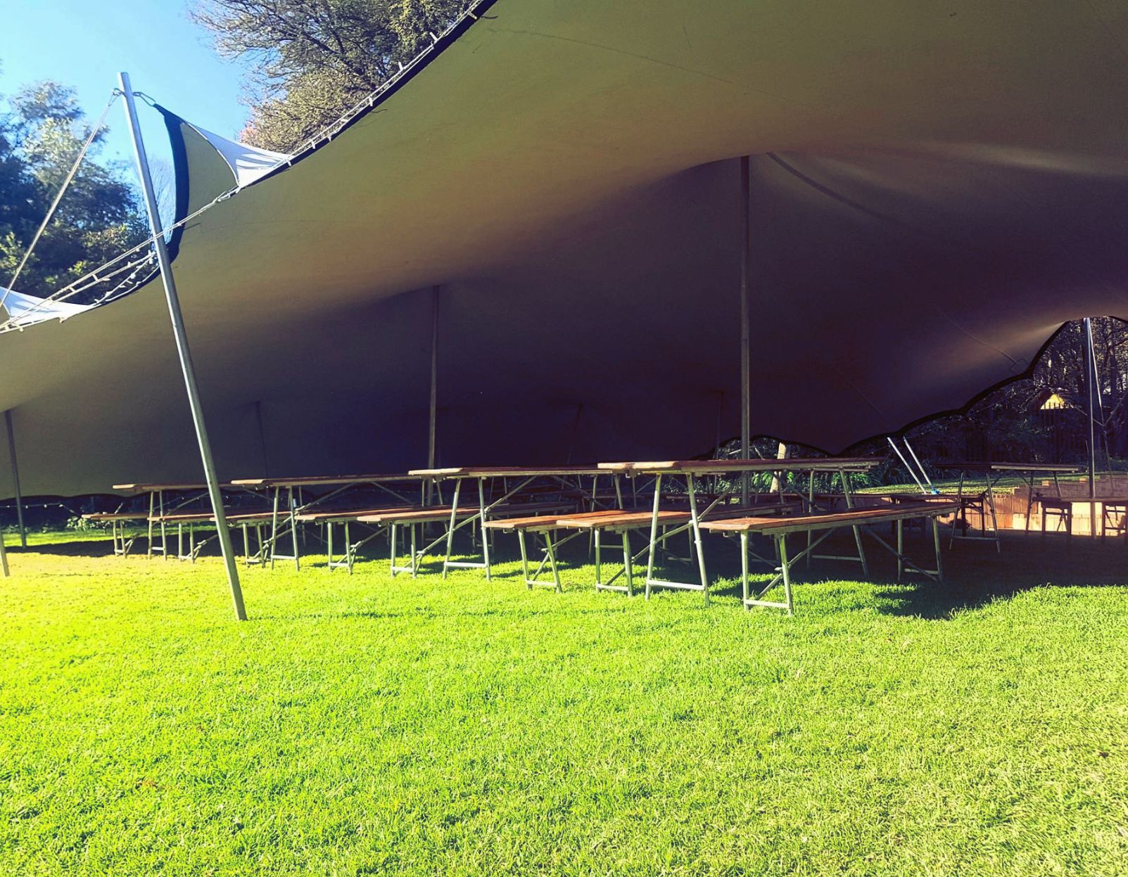 Large Tent Canopy With Benches On Grass.