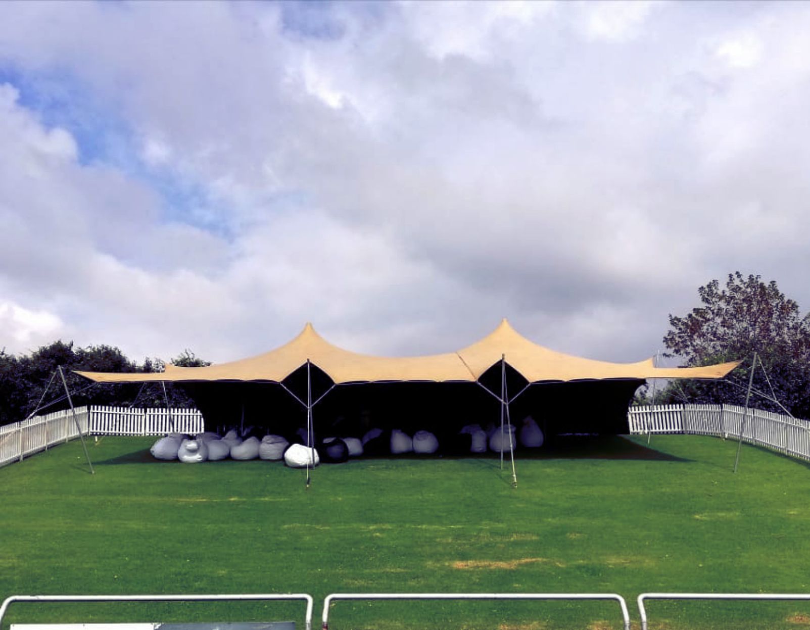 Stretch Tent With Beanbags Underneath And White Picket Fence.