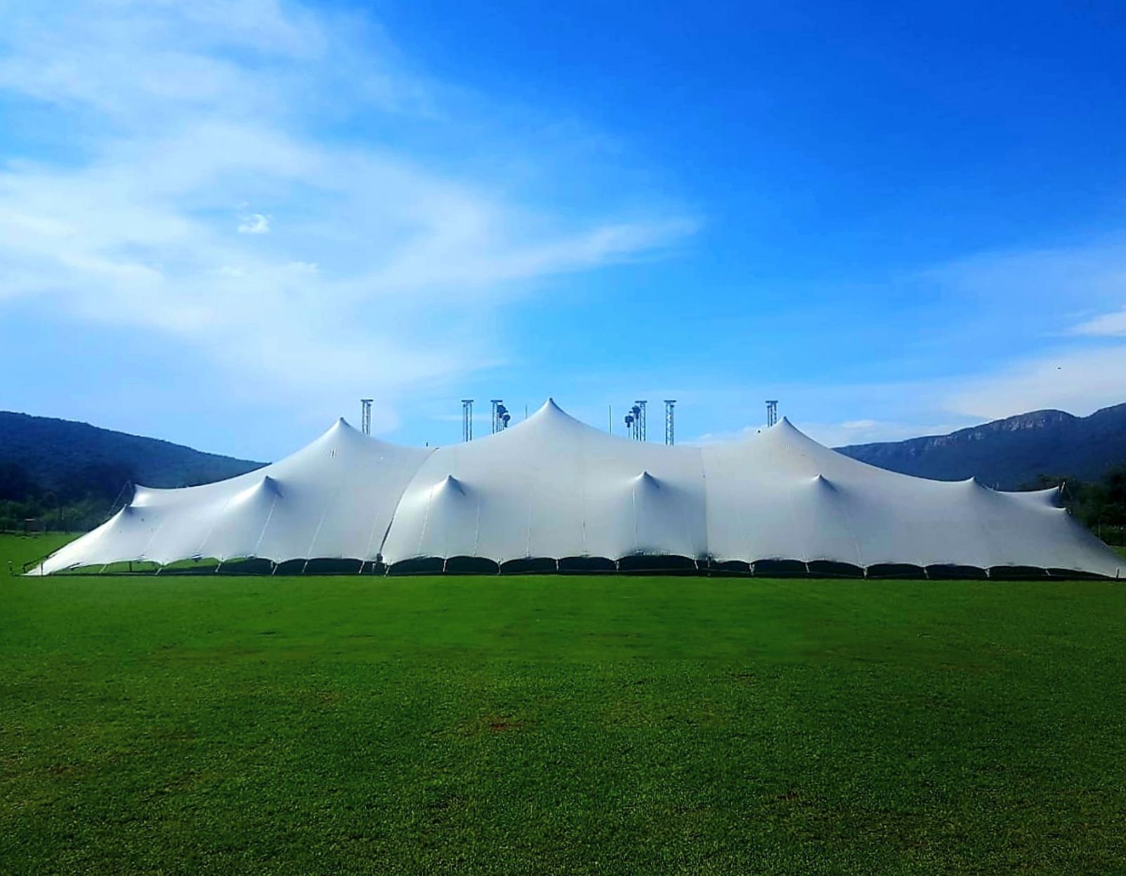 Large Stretch Tent On A Sports Field With Mountains In The Background.